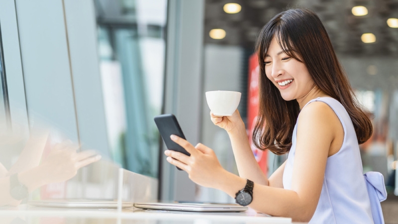 lady is drinking tea and looking in to her mobile